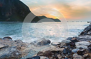 Sunrise over rocky beach and mountain background