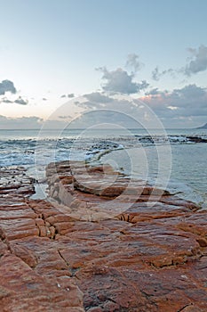 Sunrise over rocky coast at Dale Brook Tidal Swim Pool seawall in Cape Town South Africa SA