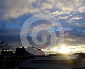 Sunrise over rooftops and a blue sky with white clouds