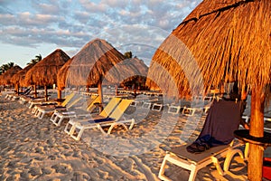 Sunrise over rows of lounge chairs and parasols at a Caribbean beach vacation