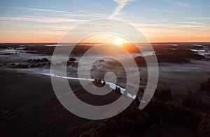 Sunrise over rural landscape with fog and river.