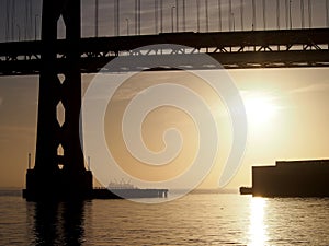 Sunrise over San Francisco Bay and through the Bay Bridge with boats in the water