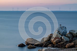 Sunrise over sea and some wind power plants