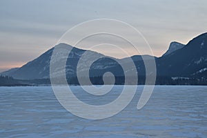 Pink Sunrise over a snowy mountain peak with frozen lake in the