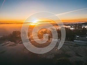 Sunrise over spring meadow. Spring aerial landscape. Spring sunrise over green forest and field with river and fog.