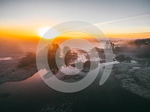 Sunrise over spring meadow. Spring aerial landscape. Spring sunrise over green forest and field with river and fog.