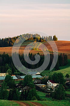 Sunrise over the village. Below are the house and the top, the sun lit mountain. Udmurtiya, Russia