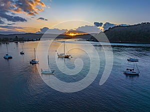 Sunrise over the water with clouds and boats