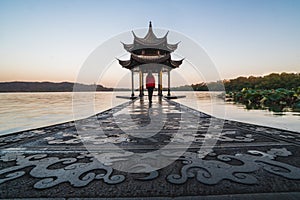 Sunrise panoramic view of the West Lake in Hangzhou, China. Girl silhouette in sunrise colors