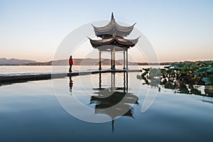 Sunrise panoramic view of the West Lake in Hangzhou, China. Girl silhouette in sunrise colors