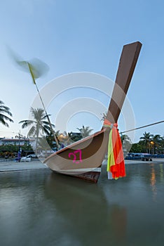 Sunrise at Patong Beach in Phuket with long-tail boat close-up and the water