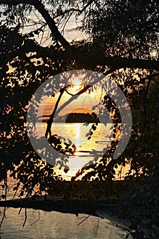Sunrise through peephole in trees over Rend Lake in Illinois