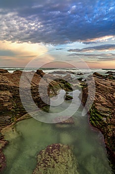 Sunrise at the Playa de las Catedrales Beach in Galicia in northern Spain with tidal pools in the foreground