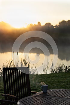 Sunrise ritual, breakfast outdoor, drinking tea or coffee early morning by the lake or pond