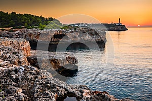Sunrise with rocks and Porto colom lighthouse photo