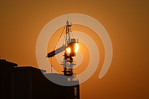 Sunrise scene housing society construction site crane machinary orange Sun and Skyline silhouette morning dawn day photography.