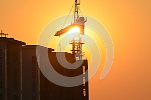 Sunrise scene housing society construction site crane machinary orange Sun and Skyline silhouette morning dawn day photography.