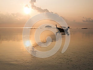 Sunrise at sea orange sky sun, long tail boat and cloud reflect with sea. Peaceful and relax feeling at tropical sea