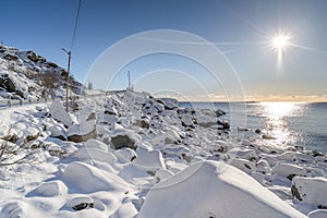 Sunrise from the sea in snowy road along the shore.