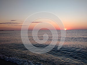 Sunrise seen from a beach rushed by sea waves photo