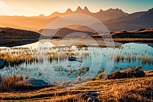 Sunrise shines over Lac Guichard with Arves massif and lake reflection in autumn at Aiguilles d\'Arves, French Alps, France