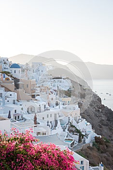 A sunrise shot of Oia village in Santorini island, Greece. Hotels and white buildings with blue dome churches in the background