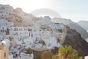 A sunrise shot of Oia village in Santorini island, Greece. Hotels and white buildings with blue dome churches in the background