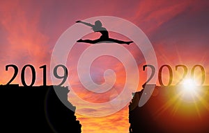 Sunrise Silhouette of Girl Leaping Over Cliff Toward New Year 2020 photo
