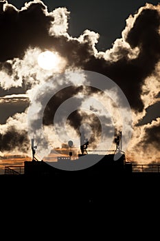 Sunrise with silhouettes of a communication antenna with satellite dishes on the roof of a skyscraper