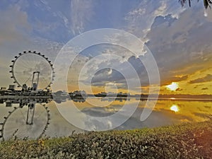 Sunrise or sunset with ferris wheel on reflection