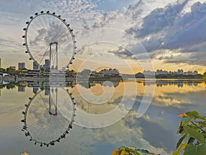 Sunrise or sunset with ferris wheel on reflection on water