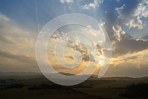 Sunrise or sunset over the hills and meadow.