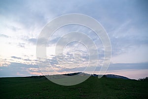 Sunrise or sunset over the hills and meadow.