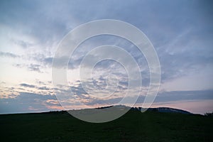 Sunrise or sunset over the hills and meadow.