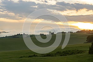 Sunrise or sunset over the hills and meadow.