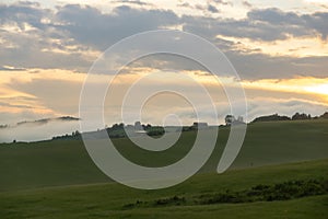 Sunrise or sunset over the hills and meadow.