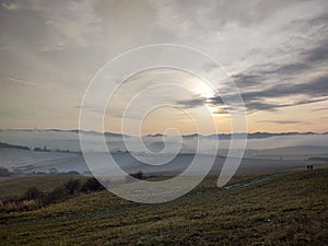 Sunrise or sunset over the hills and meadow.