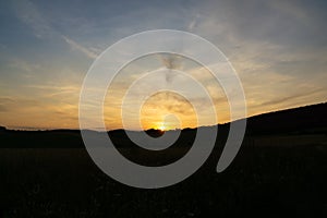 Sunrise or sunset over the hills and meadow.