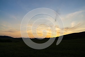 Sunrise or sunset over the hills and meadow.