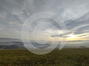 Sunrise or sunset over the hills and meadow.