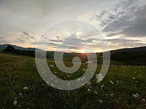 Sunrise or sunset over the hills and meadow.