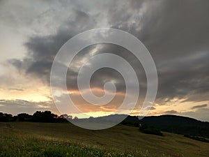 Sunrise or sunset over the hills and meadow.