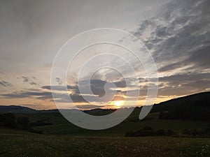 Sunrise or sunset over the hills and meadow.