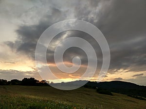 Sunrise or sunset over the hills and meadow.