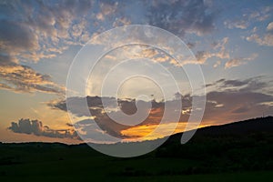 Sunrise or sunset over the hills and meadow.