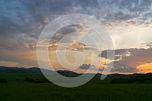 Sunrise or sunset over the hills and meadow.