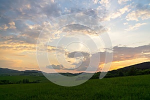 Sunrise or sunset over the hills and meadow.