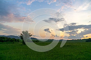 Sunrise or sunset over the hills and meadow.