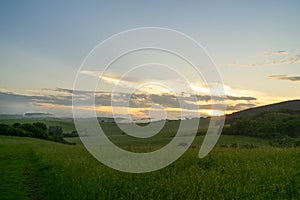 Sunrise or sunset over the hills and meadow.