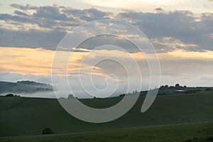 Sunrise or sunset over the hills and meadow.